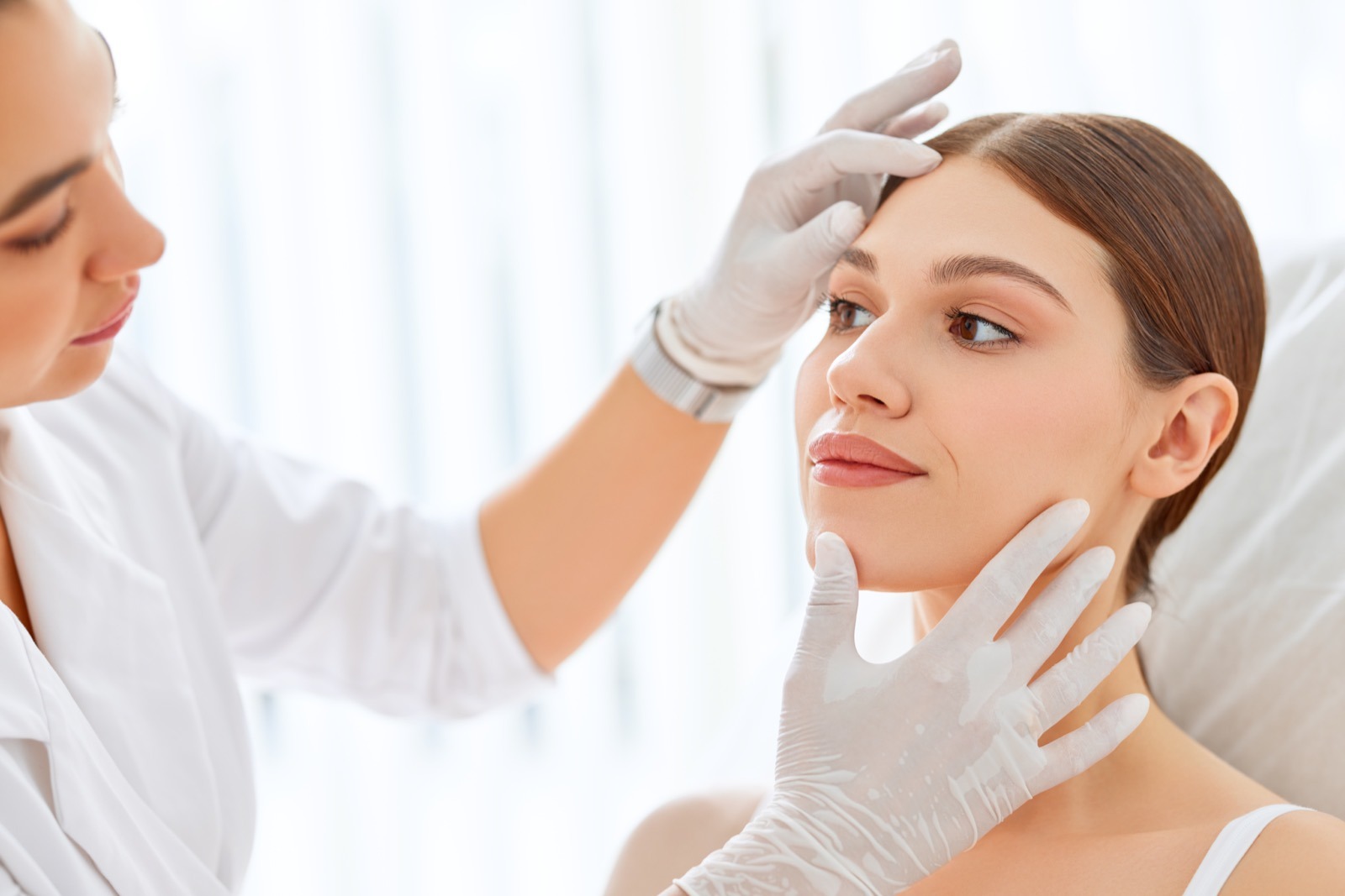 Cosmetologist examining face skin for pre-wedding Botox consultation